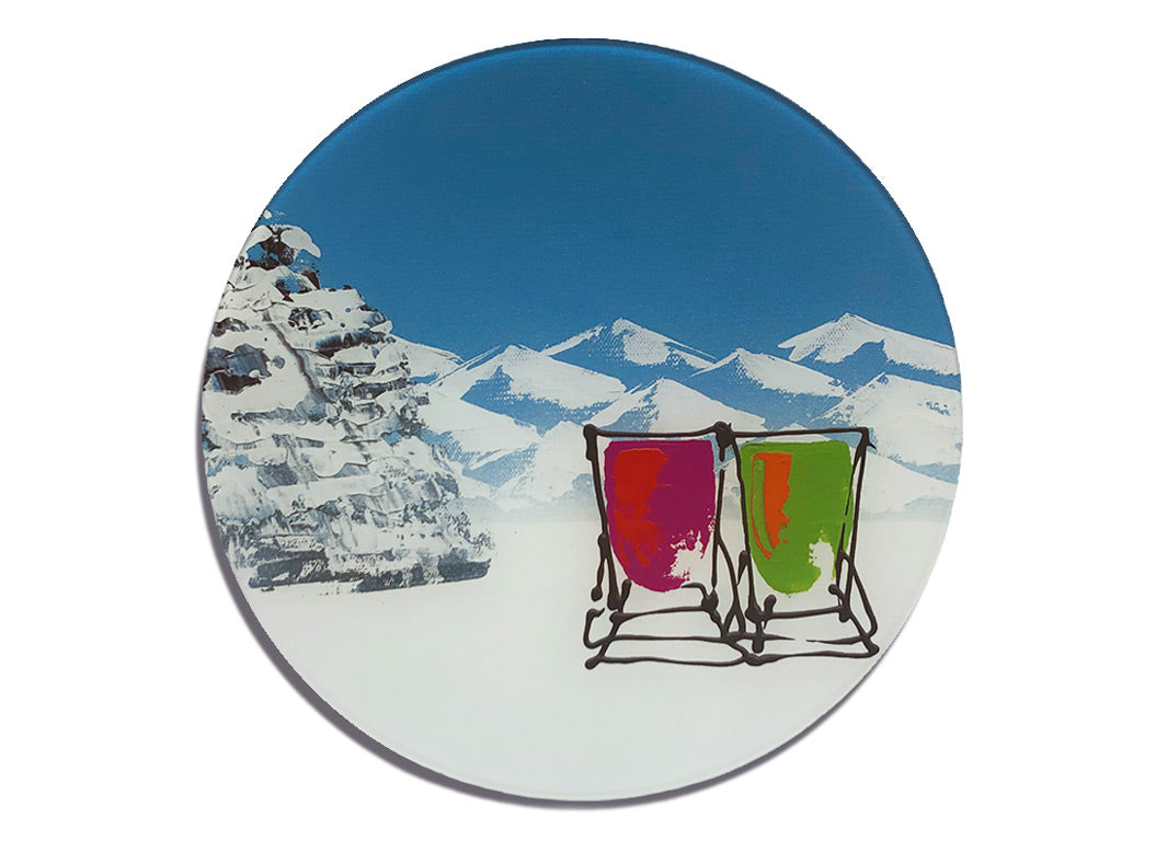 Round glass platter / worktop saver with artwork of two deckchairs in the snow with mountains backdrop by artist Hannah van Bergen