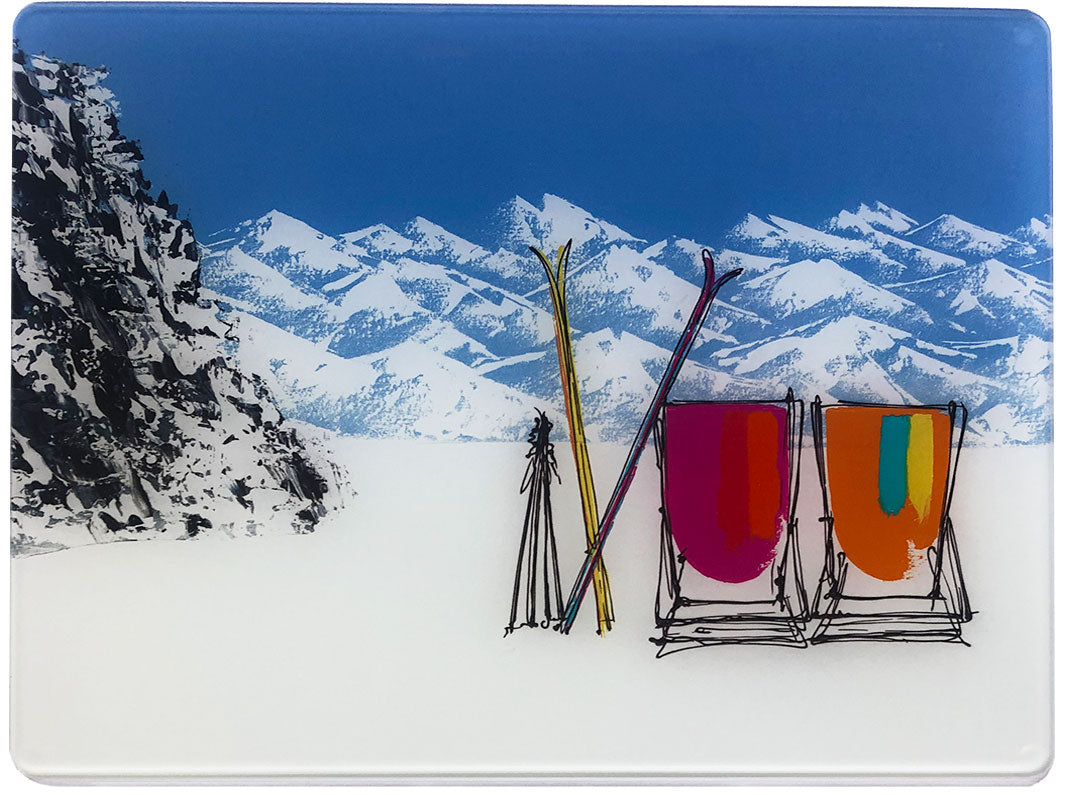 Glass platter / worktop saver with artwork of 2 deckchairs in the snow with mountain backdrop, skis and rock by artist Hannah van Bergen