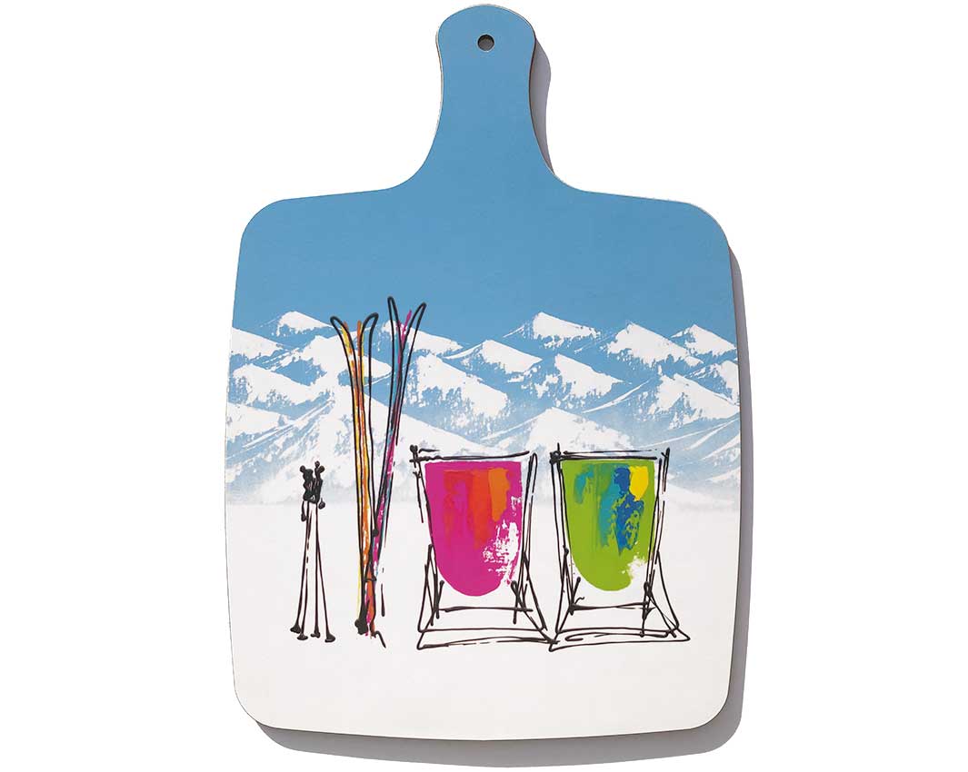 Chopping board with handle featuring 2 deckchairs in the snow with skis and mountains by artist Hannah van Bergen