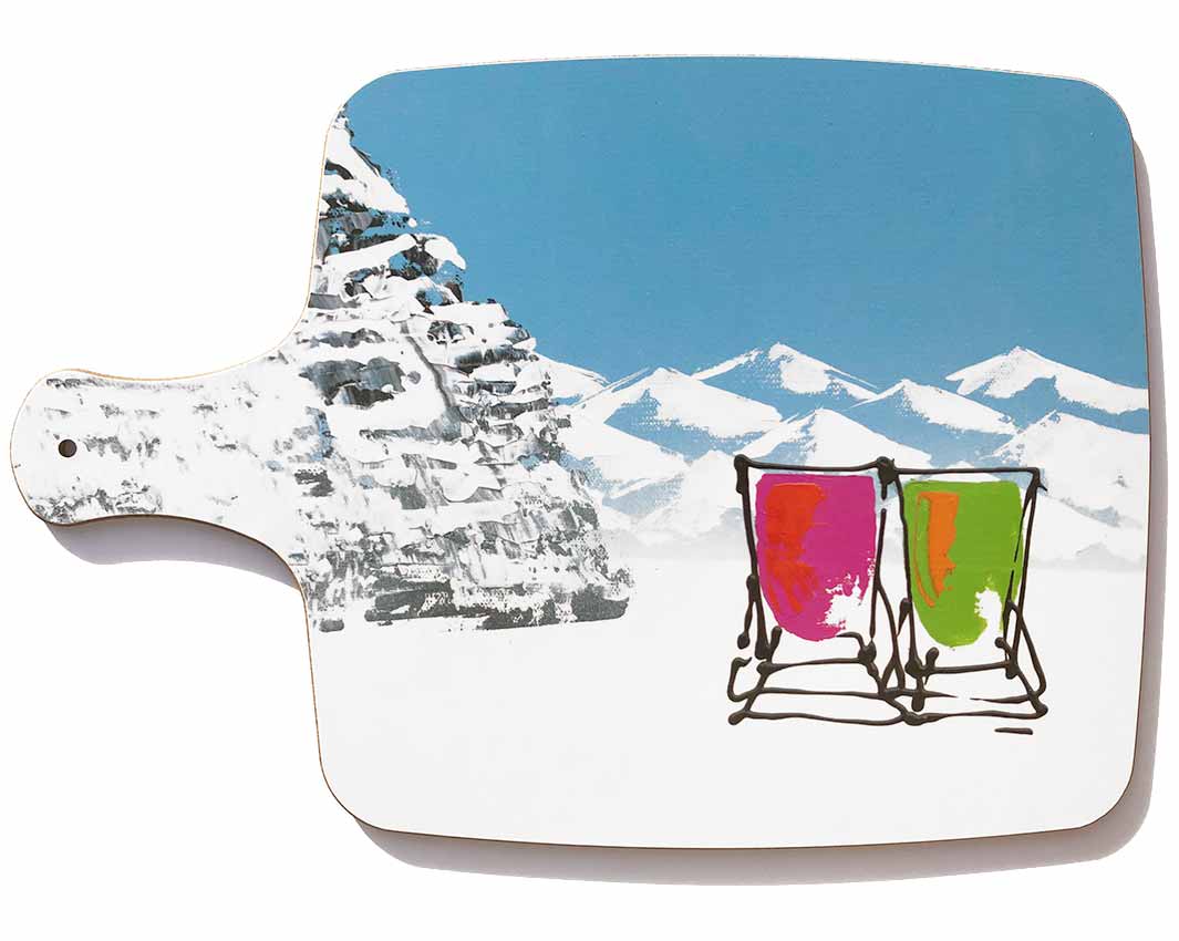Chopping board with handle featuring 2 deckchairs in the snow with blue sky and mountains by artist Hannah van Bergen