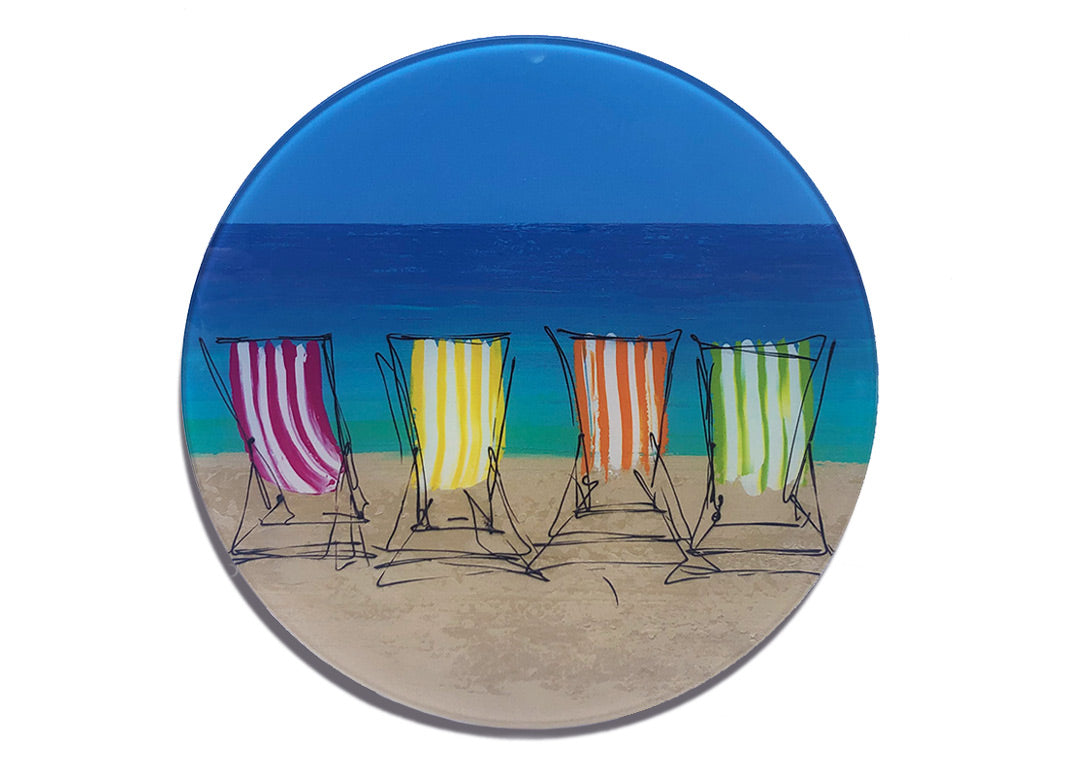 Round glass platter / worktop saver with artwork of four stripey deckchairs on a beach with sea backdrop by artist Hannah van Bergen